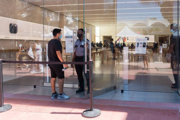 Miami Beach, Florida USA - June 16, 2020 - An employee and customer wear face masks on Lincoln Road Mall during the coronavirus pandemic.